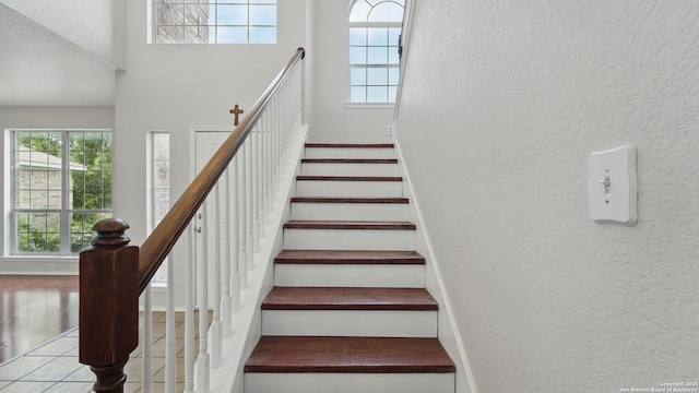 2166 Jolie, New Braunfels, TX 78130 - stairs featuring a textured wall, plenty of natural light, a towering ceiling, and wood finished floors