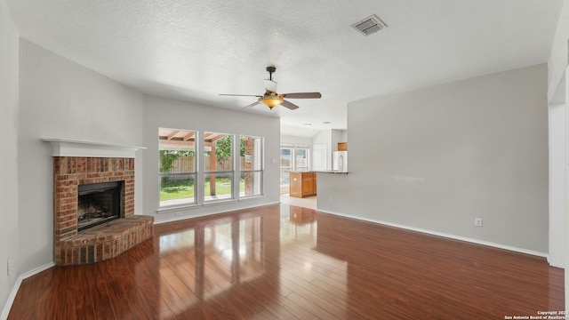 2166 Jolie, New Braunfels, TX 78130 - unfurnished living room featuring ceiling fan, wood finished floors, a fireplace, and a textured ceiling