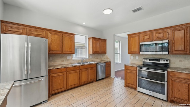 2166 Jolie, New Braunfels, TX 78130 - kitchen featuring stainless steel appliances, brown cabinets, tasteful backsplash, light wood-style floors, and recessed lighting