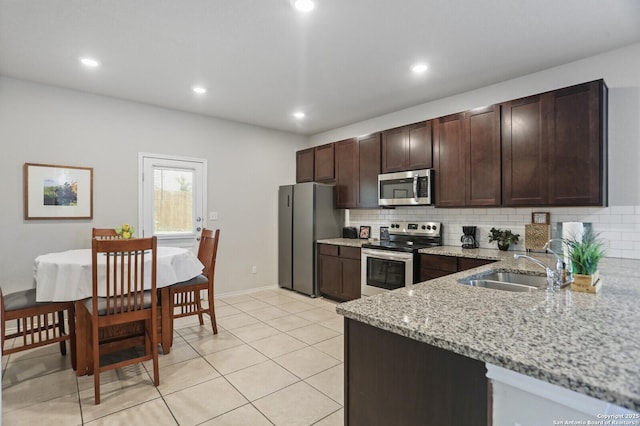 7883 Abbey, San Antonio, TX 78218 - kitchen featuring appliances with stainless steel finishes, backsplash, dark brown cabinetry, light stone counters, and recessed lighting