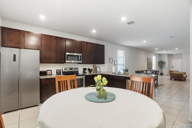 7883 Abbey, San Antonio, TX 78218 - kitchen featuring stainless steel appliances, light tile patterned floors, dark brown cabinetry, tasteful backsplash, and a peninsula