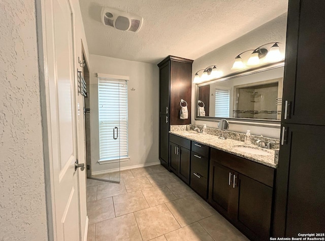 15115 Mission Oaks St, San Antonio, TX 78232 - bathroom featuring a textured ceiling, double vanity, a textured wall, and tile patterned floors
