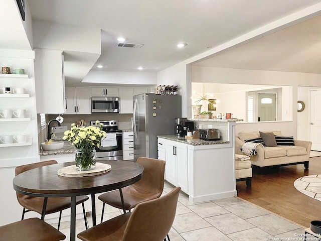 15115 Mission Oaks St, San Antonio, TX 78232 - kitchen featuring appliances with stainless steel finishes, tasteful backsplash, light stone countertops, a peninsula, and recessed lighting