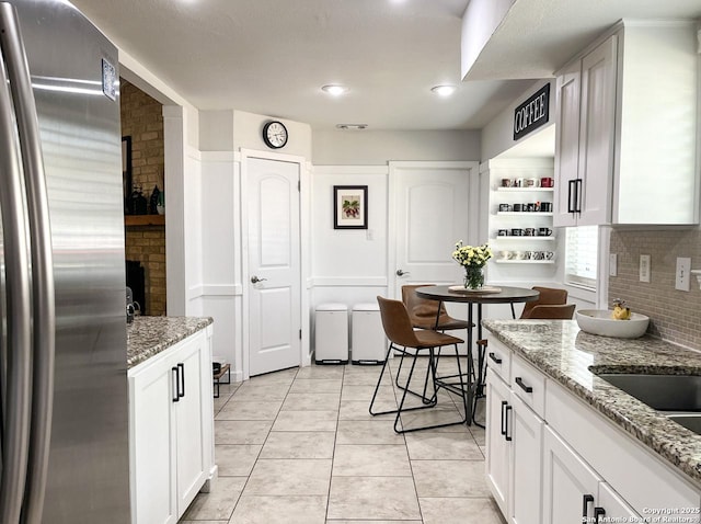 15115 Mission Oaks St, San Antonio, TX 78232 - kitchen with freestanding refrigerator, backsplash, light tile patterned flooring, white cabinets, and light stone counters