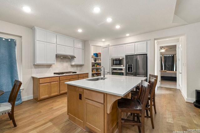 1845 Nettletree, New Braunfels, TX 78132 - kitchen featuring stainless steel appliances, light wood finished floors, light countertops, tasteful backsplash, and a kitchen bar