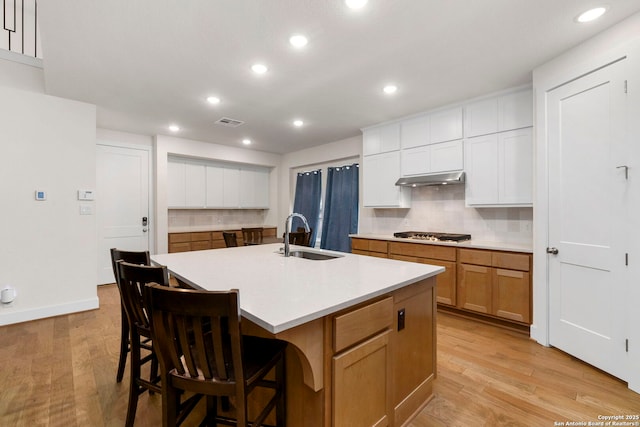 1845 Nettletree, New Braunfels, TX 78132 - kitchen with tasteful backsplash, under cabinet range hood, stainless steel gas cooktop, light wood-style flooring, and recessed lighting