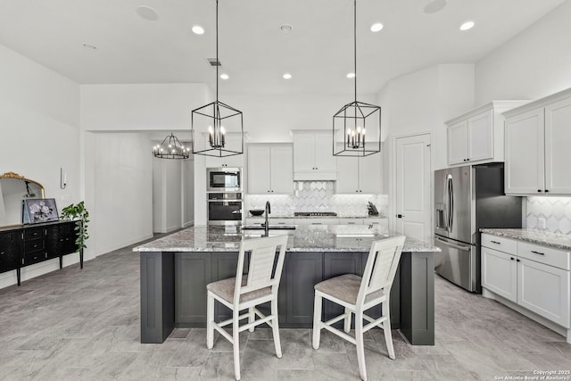 2905 Harvest Moon, Seguin, TX 78155 - kitchen with stainless steel appliances, a chandelier, a kitchen island with sink, decorative backsplash, and white cabinetry