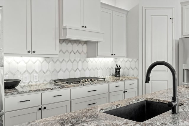 2905 Harvest Moon, Seguin, TX 78155 - kitchen with light stone counters, white cabinets, appliances with stainless steel finishes, tasteful backsplash, and premium range hood