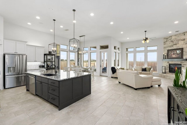 2905 Harvest Moon, Seguin, TX 78155 - kitchen featuring appliances with stainless steel finishes, a ceiling fan, recessed lighting, a stone fireplace, and light stone counters