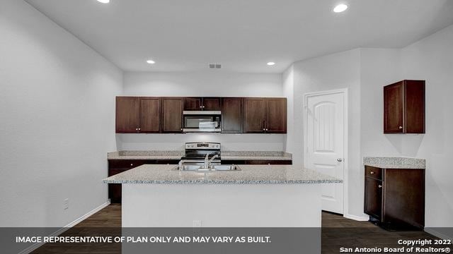 21039 Watercourse Way, San Antonio, TX 78266 - kitchen featuring appliances with stainless steel finishes, recessed lighting, an island with sink, dark wood finished floors, and light stone countertops