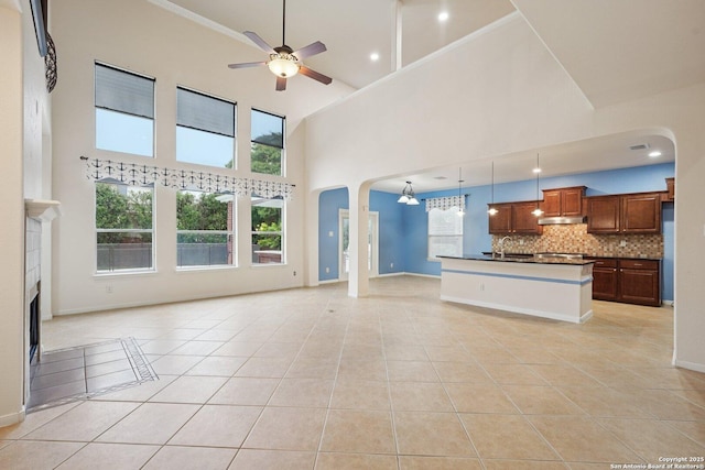 519 Catanbo, San Antonio, TX 78258 - unfurnished living room featuring a ceiling fan, light tile patterned floors, arched walkways, a high ceiling, and a fireplace
