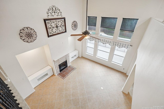 519 Catanbo, San Antonio, TX 78258 - unfurnished living room featuring a tile fireplace, light tile patterned flooring, ceiling fan, and a high ceiling