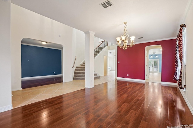 519 Catanbo, San Antonio, TX 78258 - unfurnished living room featuring arched walkways, wood finished floors, stairway, a chandelier, and crown molding