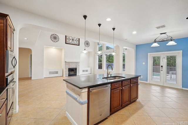 519 Catanbo, San Antonio, TX 78258 - kitchen featuring stainless steel appliances, arched walkways, a tiled fireplace, light tile patterned flooring, and decorative light fixtures