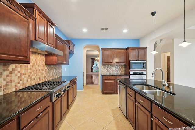 519 Catanbo, San Antonio, TX 78258 - kitchen featuring arched walkways, stainless steel appliances, under cabinet range hood, tasteful backsplash, and decorative light fixtures