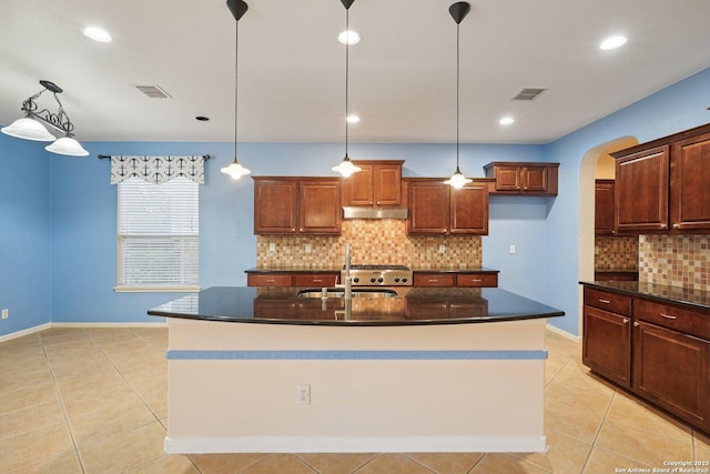 519 Catanbo, San Antonio, TX 78258 - kitchen with arched walkways, tasteful backsplash, light tile patterned floors, a kitchen island with sink, and decorative light fixtures
