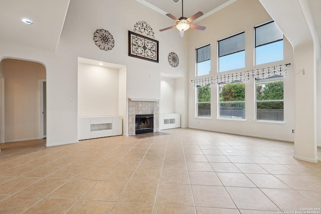 519 Catanbo, San Antonio, TX 78258 - unfurnished living room with tile patterned floors, ceiling fan, arched walkways, a high ceiling, and crown molding