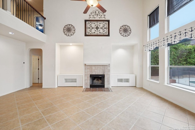 519 Catanbo, San Antonio, TX 78258 - unfurnished living room with a high ceiling, ceiling fan, arched walkways, tile patterned flooring, and a tiled fireplace