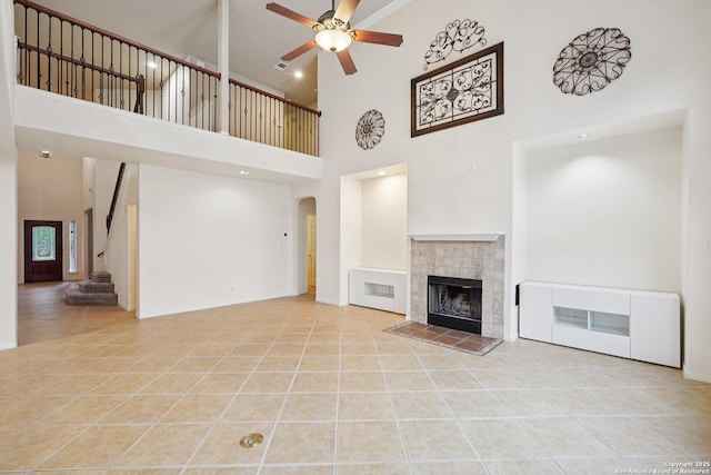 519 Catanbo, San Antonio, TX 78258 - unfurnished living room with a high ceiling, a ceiling fan, a tiled fireplace, tile patterned floors, and arched walkways