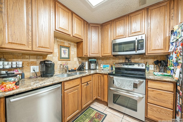 11002 Stagwood Pass, San Antonio, TX 78254 - kitchen featuring stainless steel appliances, decorative backsplash, light tile patterned floors, light stone countertops, and a textured ceiling