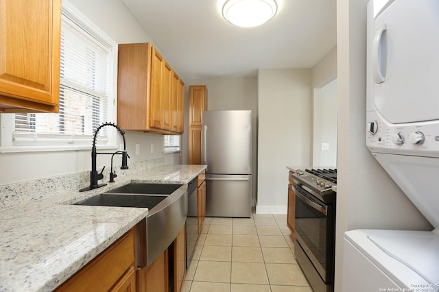 1002 Kampmann Blvd, San Antonio, TX 78201 - kitchen with stainless steel appliances, stacked washer and clothes dryer, light tile patterned floors, and light stone countertops