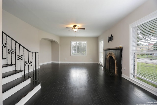 1002 Kampmann Blvd, San Antonio, TX 78201 - unfurnished living room with a ceiling fan, arched walkways, a fireplace, wood finished floors, and stairway