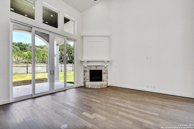 228 Dulce Vis, Boerne, TX 78006 - unfurnished living room with wood finished floors, a towering ceiling, and a stone fireplace