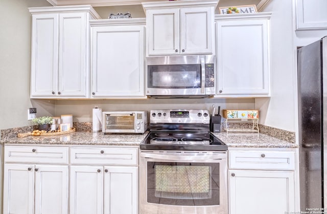 104 Sunday Ct, Uvalde, TX 78801 - kitchen featuring stainless steel appliances, light stone counters, and white cabinets