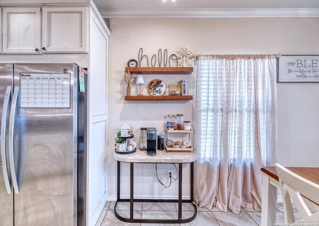 104 Sunday Ct, Uvalde, TX 78801 - kitchen featuring freestanding refrigerator, ornamental molding, light tile patterned floors, light countertops, and white cabinets