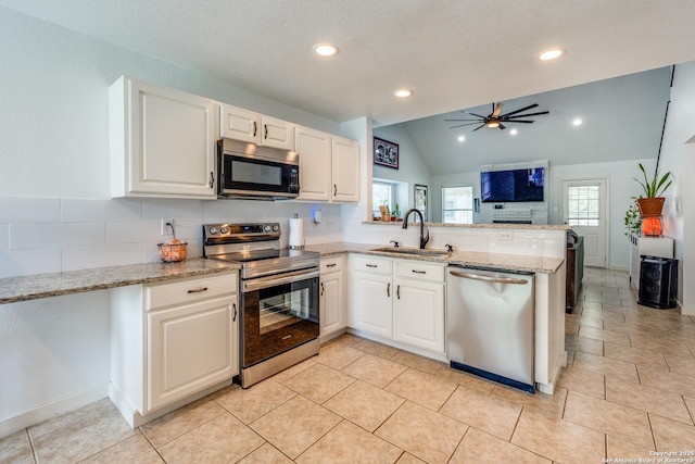 2500 Newning, Schertz, TX 78154 - kitchen featuring appliances with stainless steel finishes, a peninsula, lofted ceiling, ceiling fan, and white cabinetry