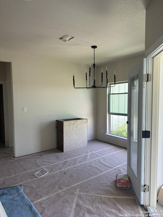 720 N Dickson, Poth, TX 78147 - unfurnished dining area featuring a chandelier, a textured ceiling, and unfinished concrete flooring