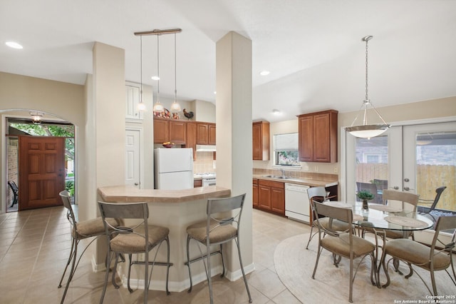 14630 Snip, San Antonio, TX 78248 - kitchen with white appliances, a breakfast bar, light countertops, light tile patterned flooring, and decorative light fixtures