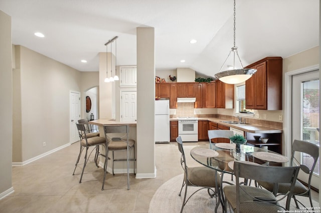 14630 Snip, San Antonio, TX 78248 - kitchen featuring white appliances, under cabinet range hood, arched walkways, pendant lighting, and vaulted ceiling