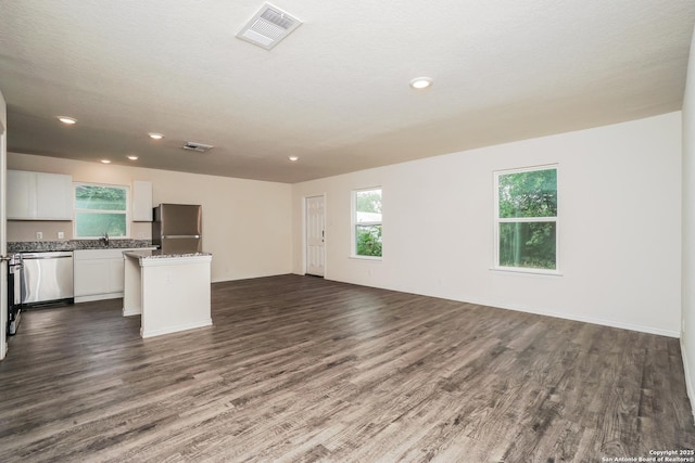 223 Baxter, Seguin, TX 78155 - unfurnished living room featuring dark wood-style flooring, healthy amount of natural light, and recessed lighting