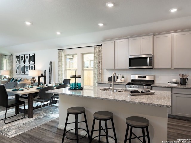 1124 Nikos Holw, San Antonio, TX 78245 - kitchen with stainless steel appliances, dark wood-style flooring, tasteful backsplash, a kitchen bar, and recessed lighting