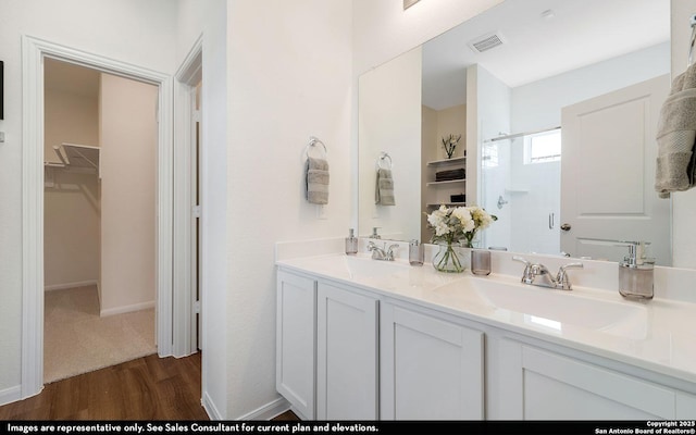 4948 Hawkwell Ln, San Antonio, TX 77584 - bathroom featuring wood finished floors, double vanity, a walk in closet, and a shower with door