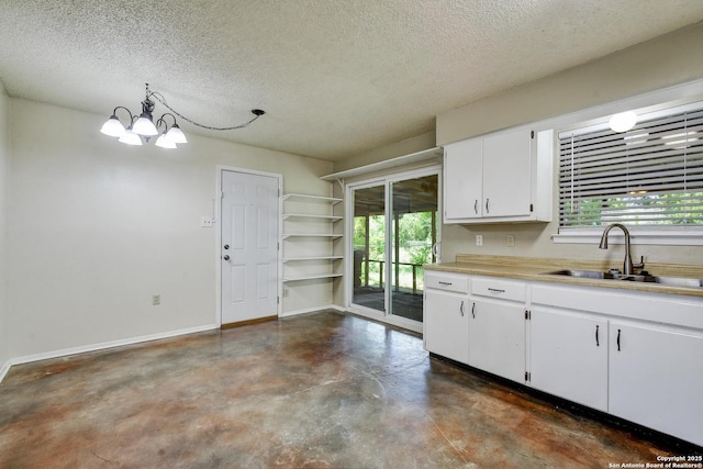 105 Apache, Cibolo, TX 78108 - kitchen with concrete floors, a chandelier, a textured ceiling, plenty of natural light, and white cabinets