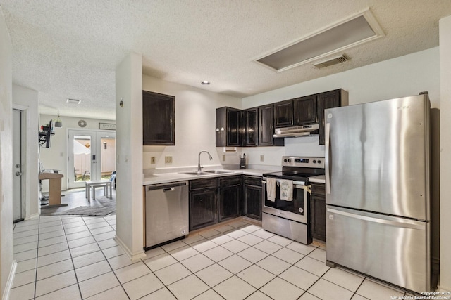 7643 Heathridge, San Antonio, TX 78250 - kitchen with appliances with stainless steel finishes, under cabinet range hood, a textured ceiling, light countertops, and light tile patterned floors