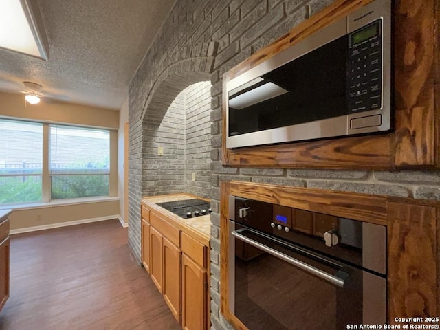 5103 Cabin Lake Dr, San Antonio, TX 78244 - kitchen with black appliances, a textured ceiling, wood finished floors, a ceiling fan, and brick wall