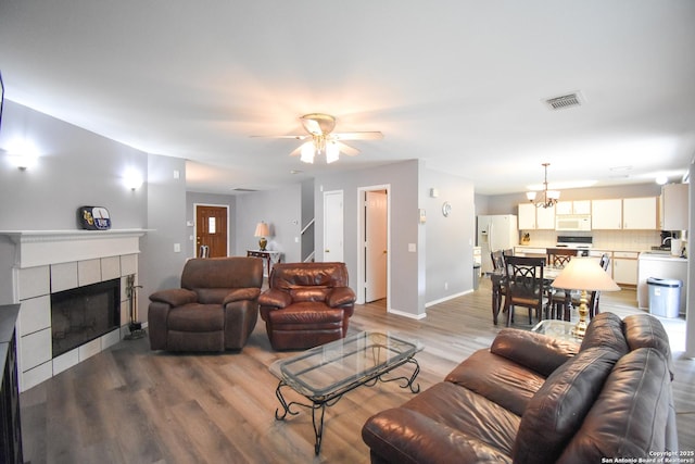 10310 Mission Crk, Converse, TX 78109 - living room featuring light wood finished floors, a tile fireplace, ceiling fan, and a chandelier