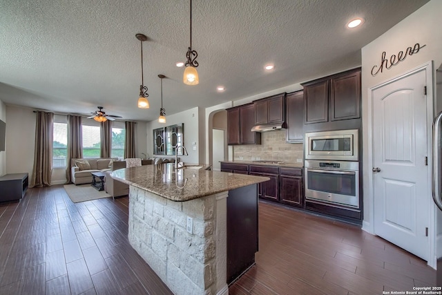 5938 Akin Song, San Antonio, TX 78261 - kitchen with appliances with stainless steel finishes, arched walkways, decorative backsplash, light stone counters, and open floor plan