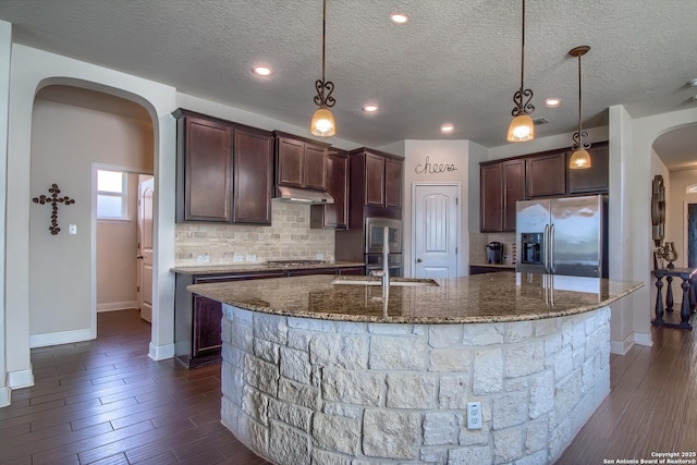 5938 Akin Song, San Antonio, TX 78261 - kitchen with stainless steel appliances, arched walkways, under cabinet range hood, backsplash, and a textured ceiling