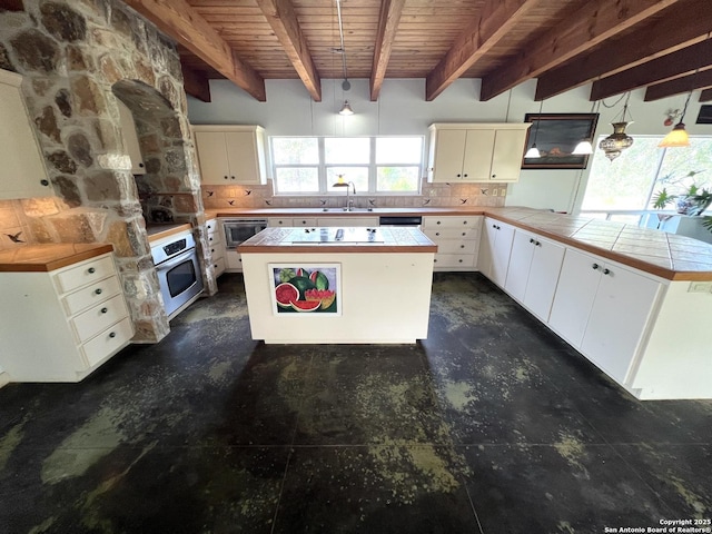 184 Guadalupe Hls, Seguin, TX 78155 - kitchen with stainless steel appliances, a wood ceiling with exposed beams, decorative backsplash, a peninsula, and concrete floors