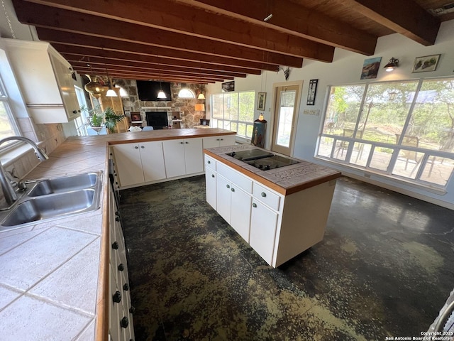 184 Guadalupe Hls, Seguin, TX 78155 - kitchen with tile countertops, black electric stovetop, white cabinetry, beam ceiling, and a fireplace