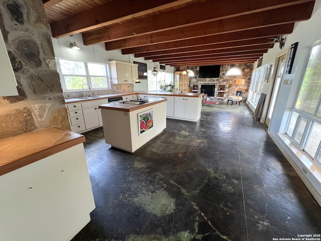 184 Guadalupe Hls, Seguin, TX 78155 - kitchen featuring beam ceiling, a stone fireplace, white cabinets, a kitchen island, and open floor plan