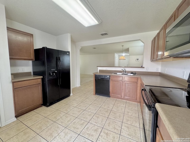 130 Palazzo Torre, San Antonio, TX 78253 - kitchen featuring black appliances, light tile patterned floors, a peninsula, a textured ceiling, and decorative light fixtures