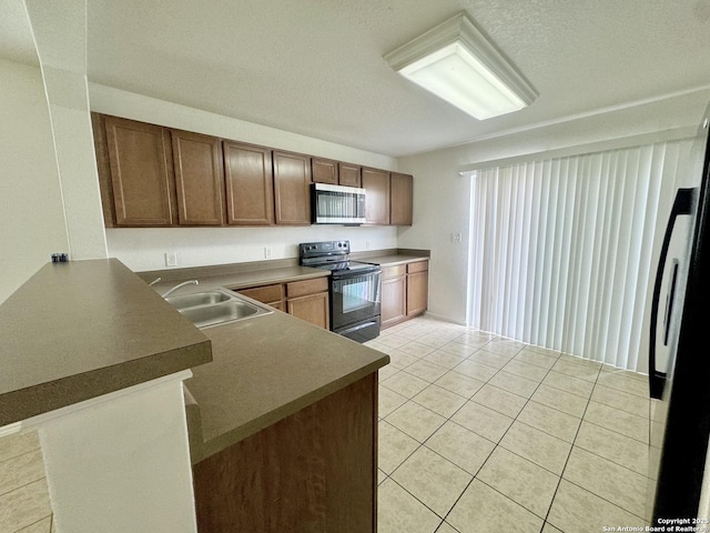 130 Palazzo Torre, San Antonio, TX 78253 - kitchen with electric range, stainless steel microwave, a peninsula, light tile patterned floors, and dark countertops