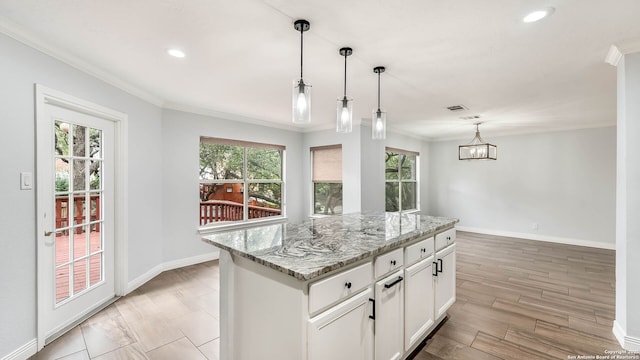 2530 Melrose Cyn, San Antonio, TX 78232 - kitchen with plenty of natural light, light stone counters, white cabinetry, ornamental molding, and a kitchen island