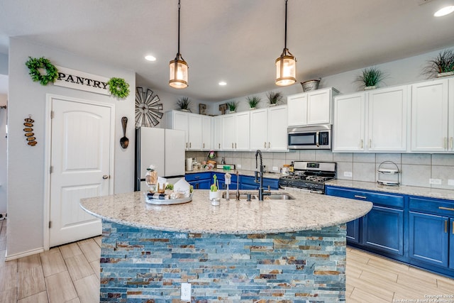 8838 Palmetto Fls, San Antonio, TX 78254 - kitchen with stainless steel appliances, blue cabinetry, decorative backsplash, white cabinets, and recessed lighting
