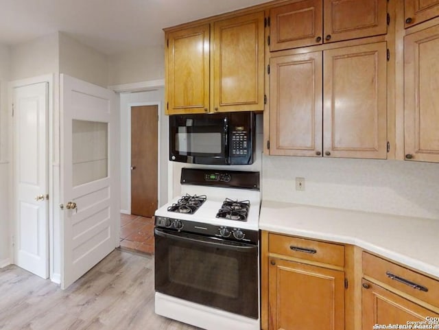 117 Bryker, Terrell Hills, TX 78209 - kitchen featuring black microwave, range with gas stovetop, light countertops, light wood-style floors, and brown cabinets